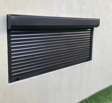 Cortina catalana de aluminio instalada en fachada urbana, con diseño tradicional y estructura resistente, ideal para seguridad y estética exterior